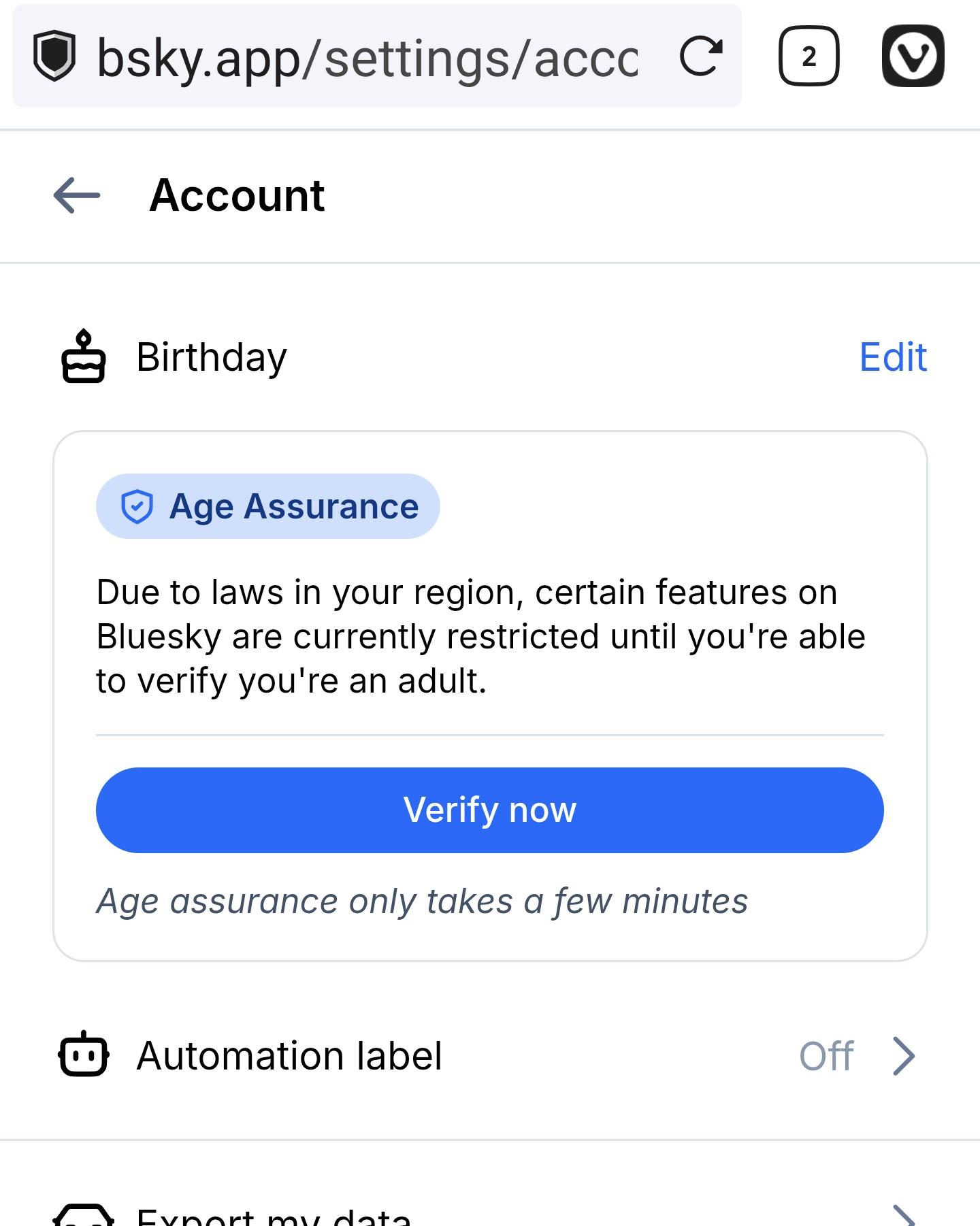 A screenshot of the Account settings page on the Bluesky web app (bsky.app).

In the center, a prominent card titled "Age Assurance" features a blue shield icon. The text reads: "Due to laws in your region, certain features on Bluesky are currently restricted until you're able to verify you're an adult." Below the text is a large blue button that says "Verify now," followed by a note stating that the process only takes a few minutes.

The surrounding interface shows other account options including "Birthday" with an Edit link, "Automation label" set to Off, and "Export my data."