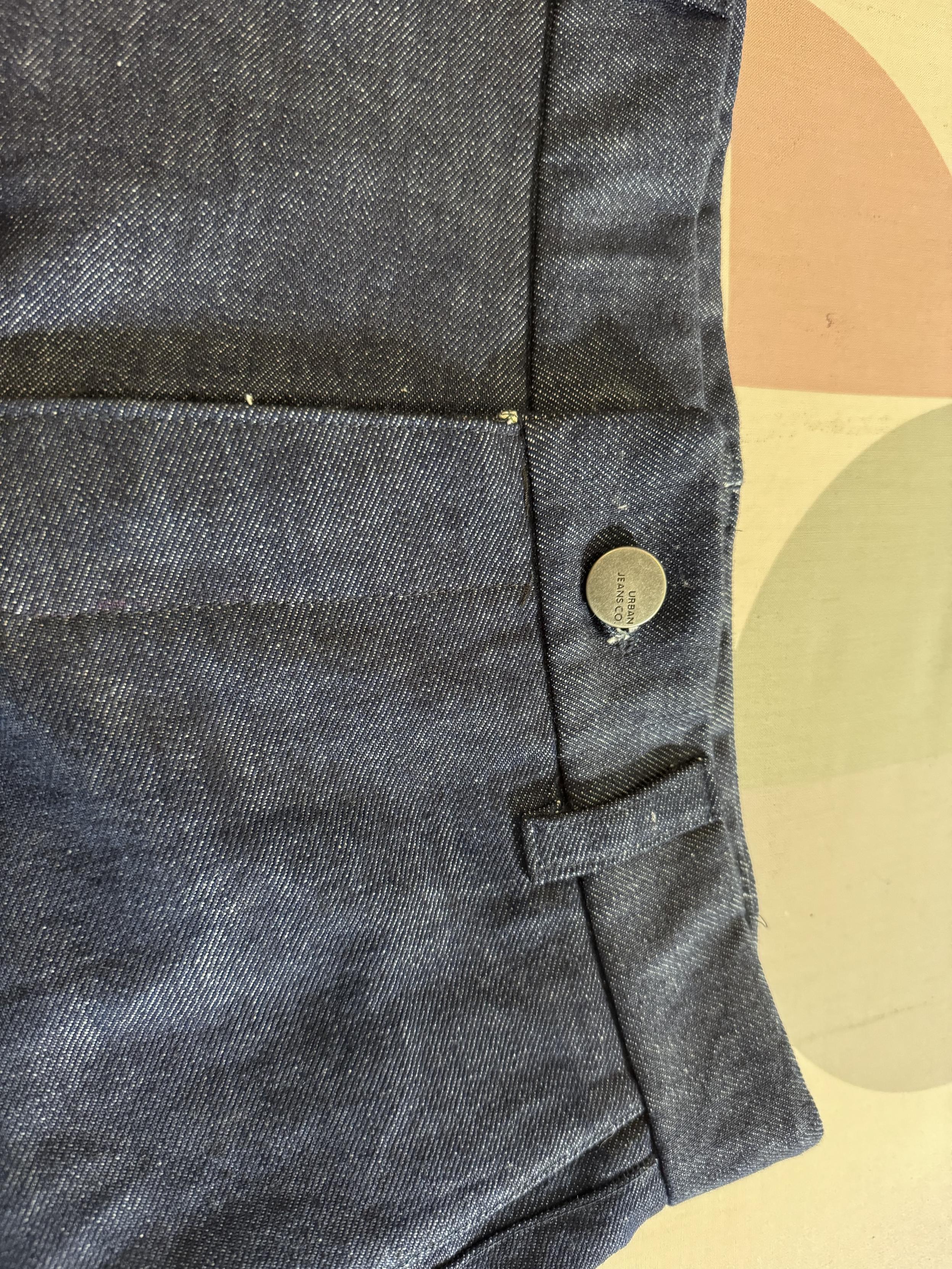 Front view of blue denim shorts with a metal button and belt loops