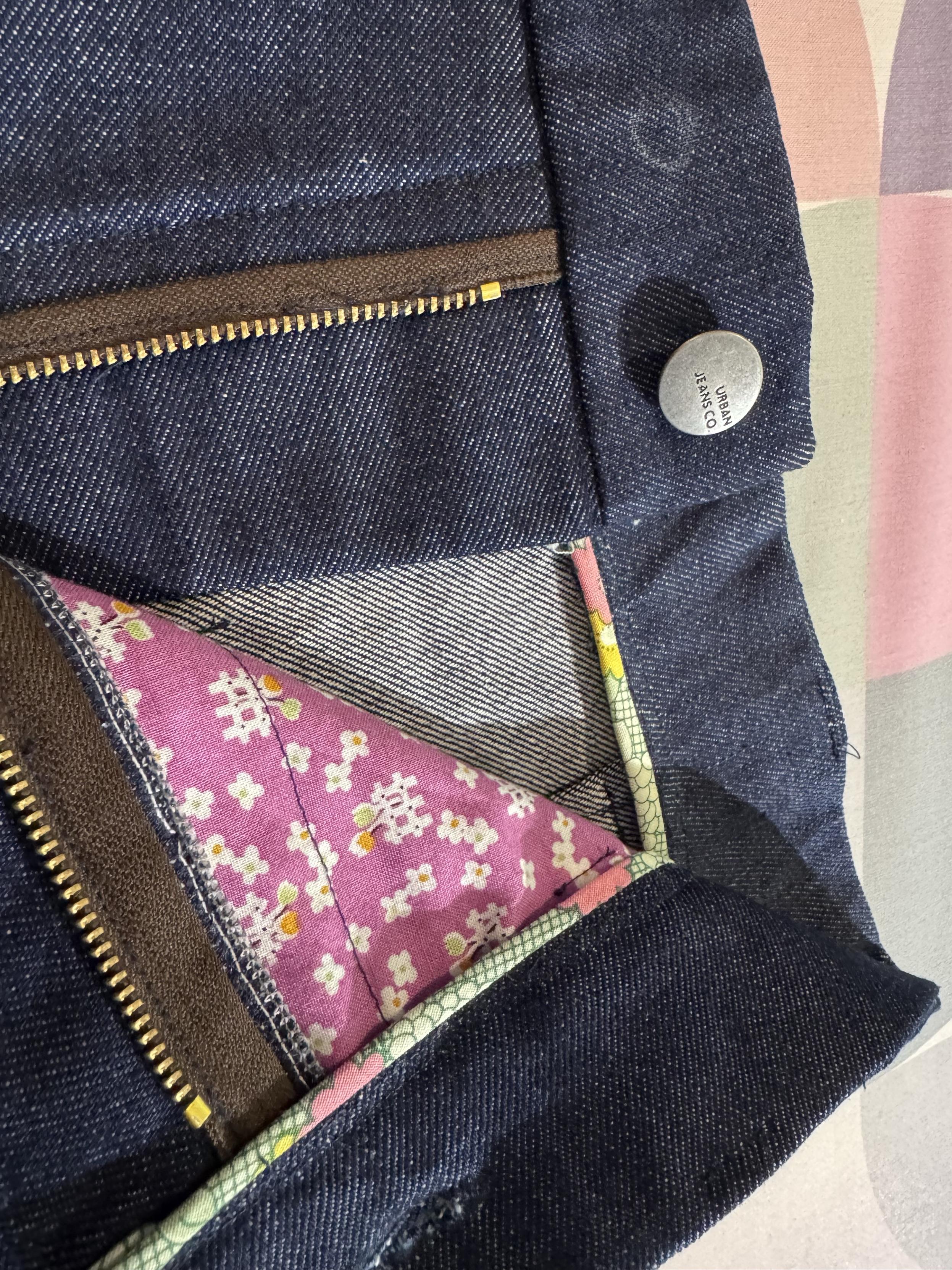 Peek at the inside of the blue denim shorts, with a light green bias binding on the inside waistband, and a purple patterned pocket.