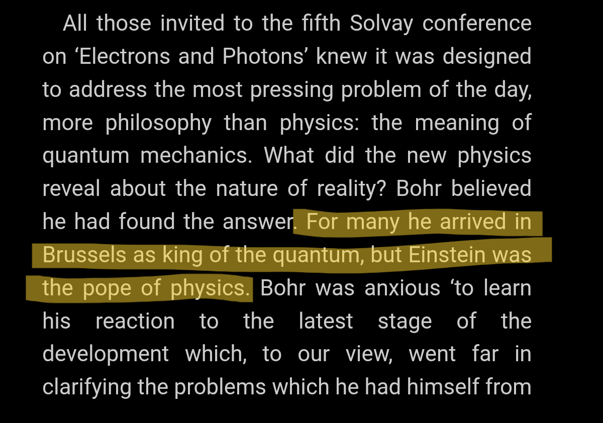 A dark-mode screenshot of text from the file Screenshot_20260524-205704_Google Play Books.png discussing the fifth Solvay conference. A single sentence is highlighted in yellow, which reads: "For many he arrived in Brussels as king of the quantum, but Einstein was the pope of physics."