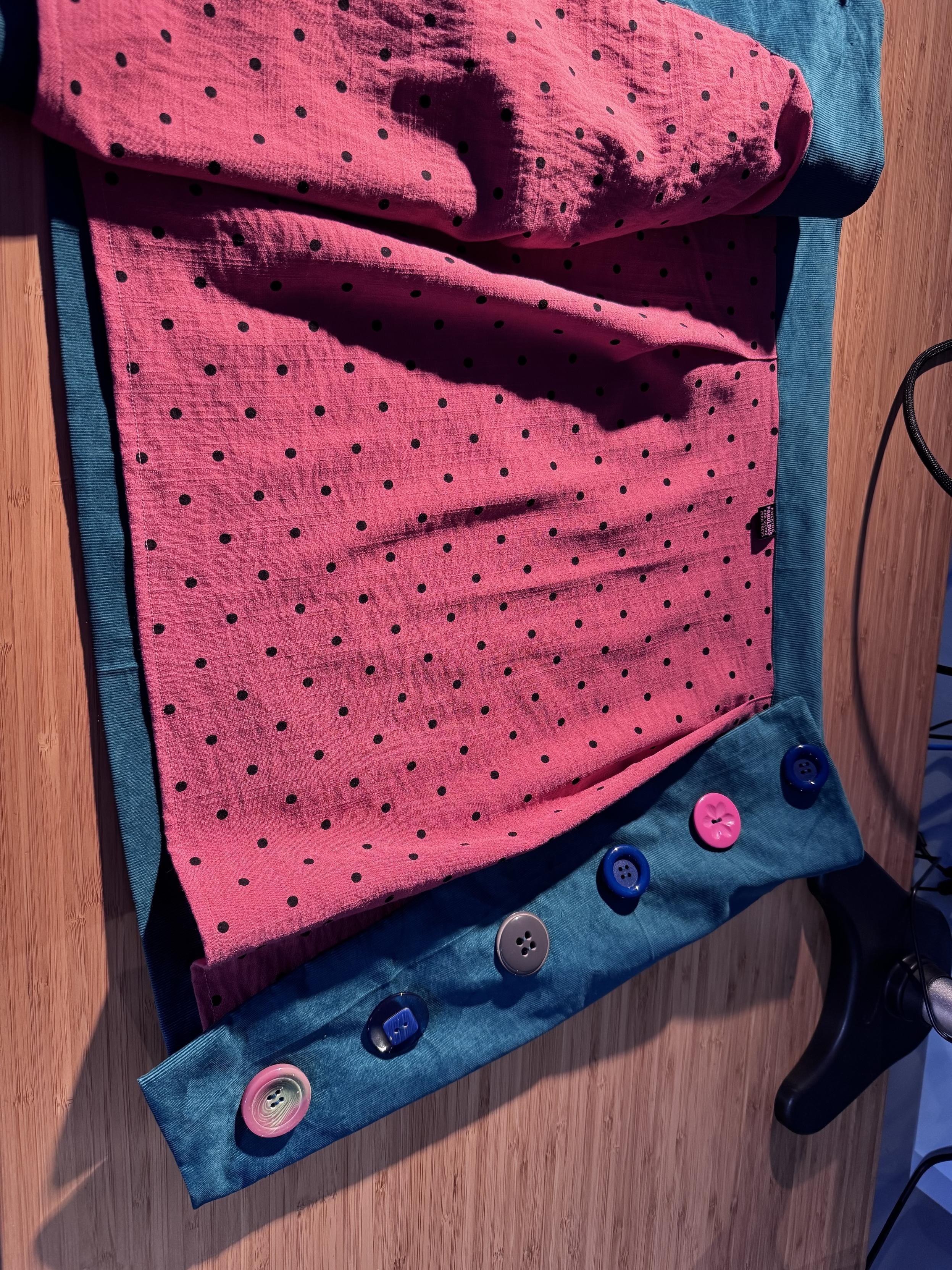 Inside view of coral coloured black polka dot lining in the teal corduroy with the buttons visible on the side
