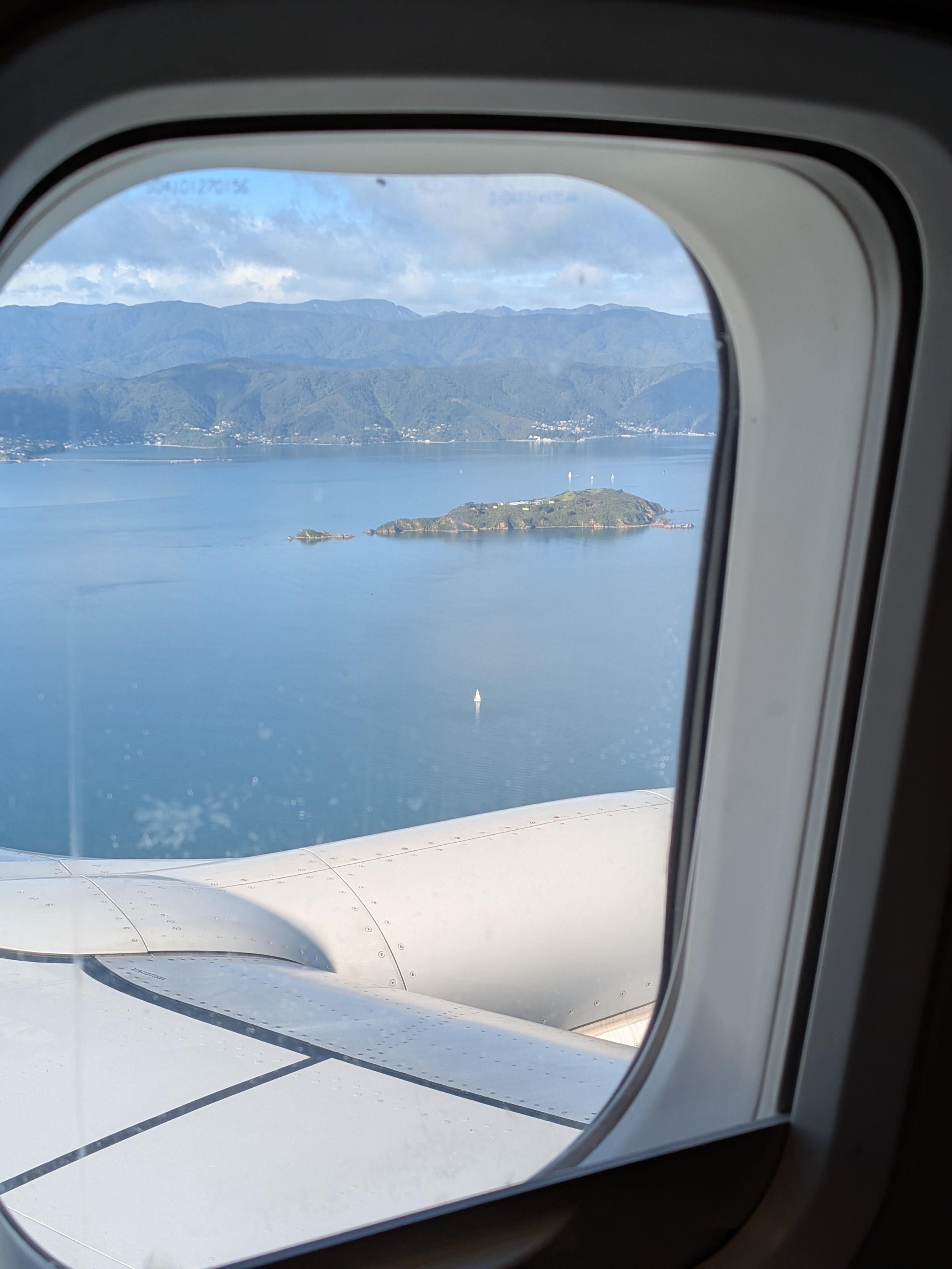 Window view of matiu/somes island. wellington harbour looks flat with a few sail boats dotted around