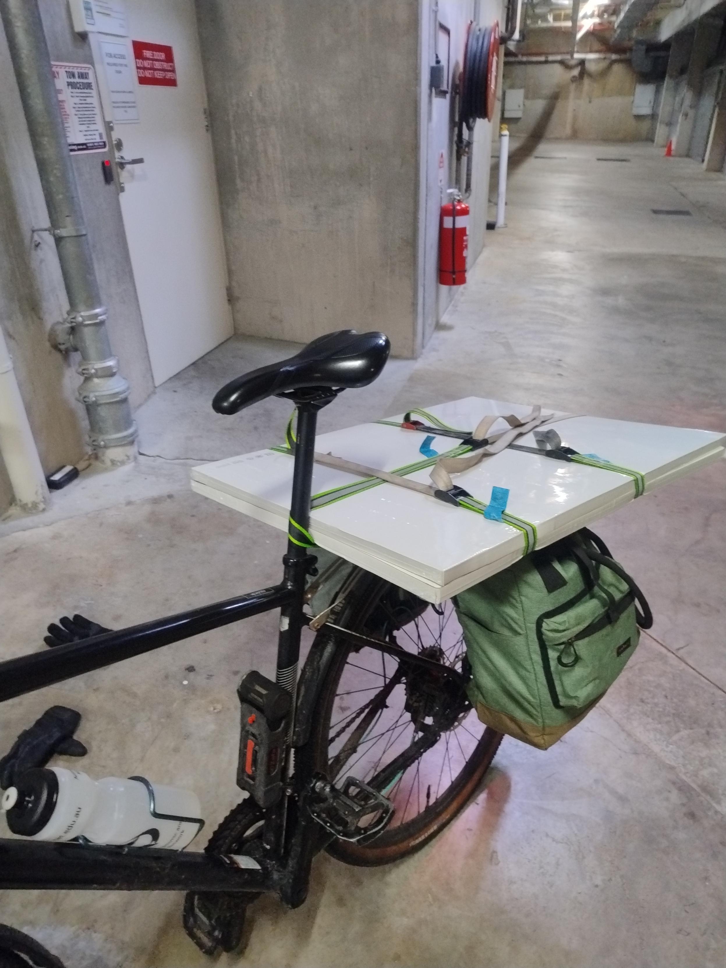 A gravel bike with 2 large, flat boxes on the rear rack, and 2 green pannier bags.

This is a 45° Angle from the front of the bike
