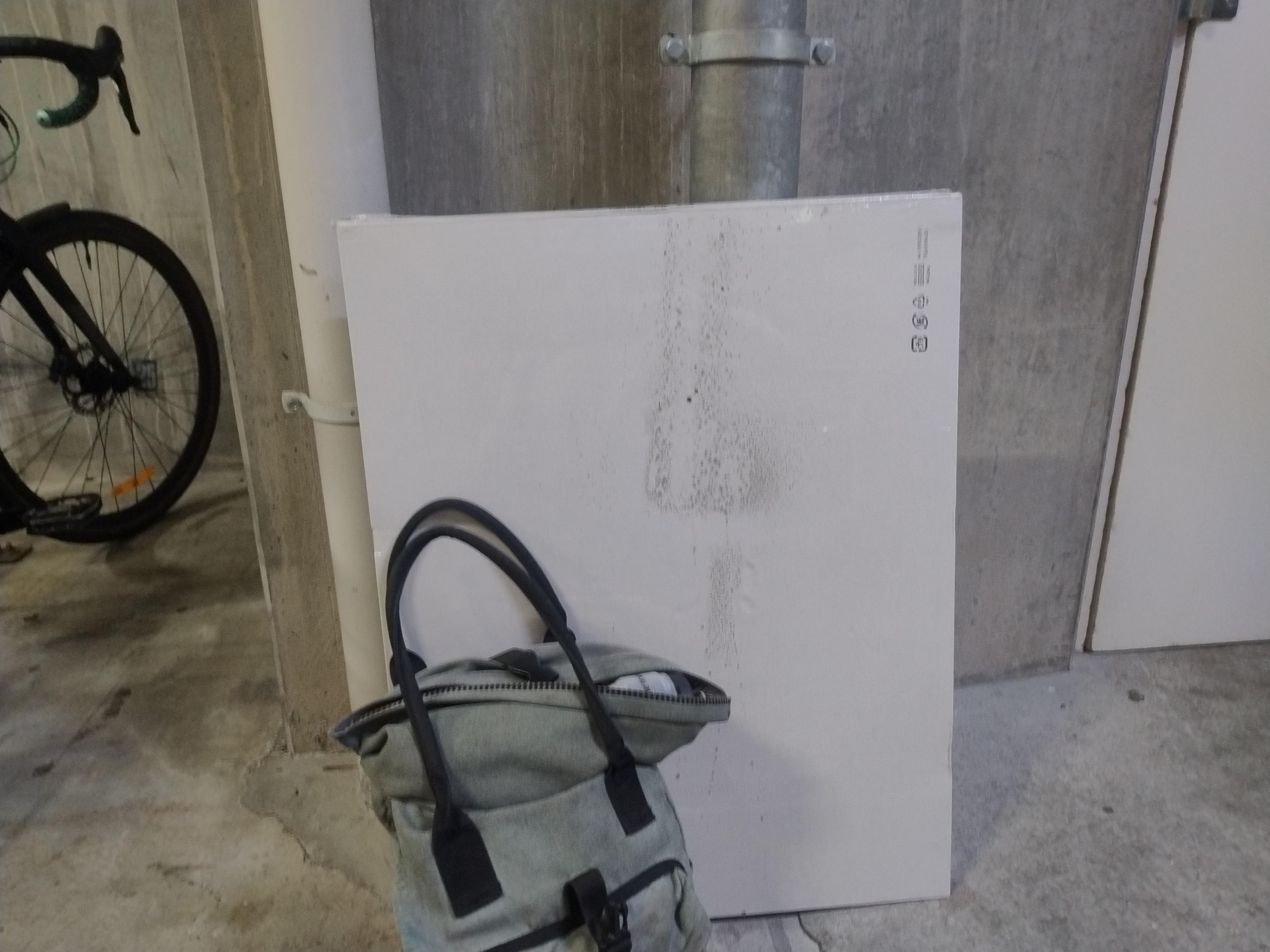 The boxes against the wall, with a mud on the back of one of the boxes. The pannier backpack is in front of it, and it looks teeny in comparison